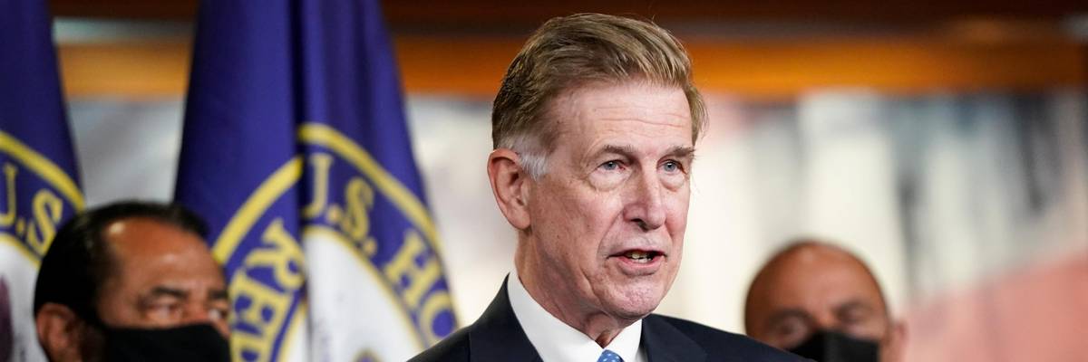 Don Beyer stands in a suit.