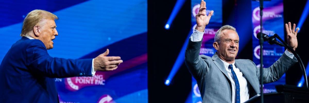 Donald Trump gestures toward Robert F. Kennedy Jr., whose hands are raised in greeting to an audience