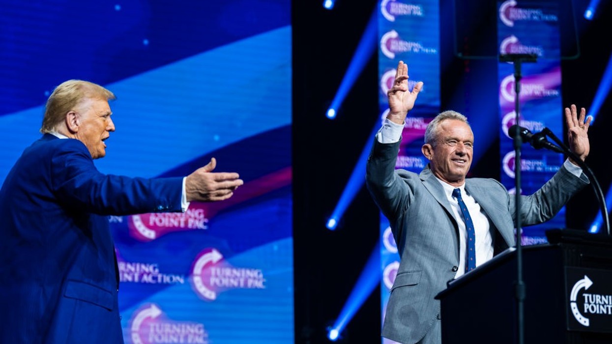 Donald Trump gestures toward Robert F. Kennedy Jr., whose hands are raised in greeting to an audience