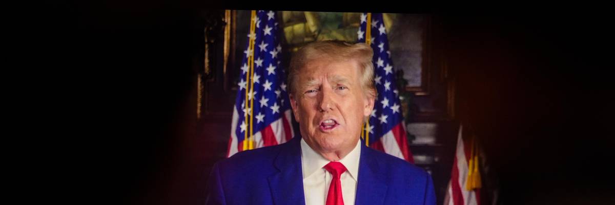 Donald Trump on a video monitor as an audience watches