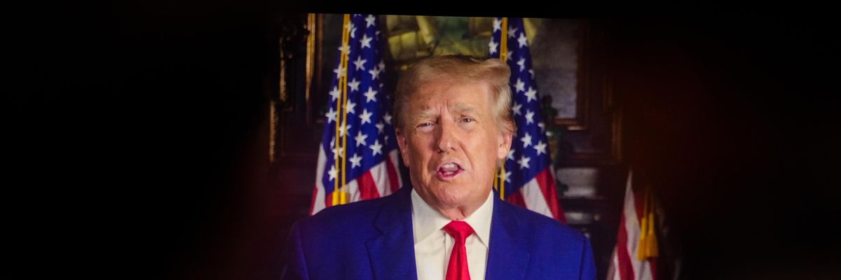 Donald Trump on a video monitor as an audience watches
