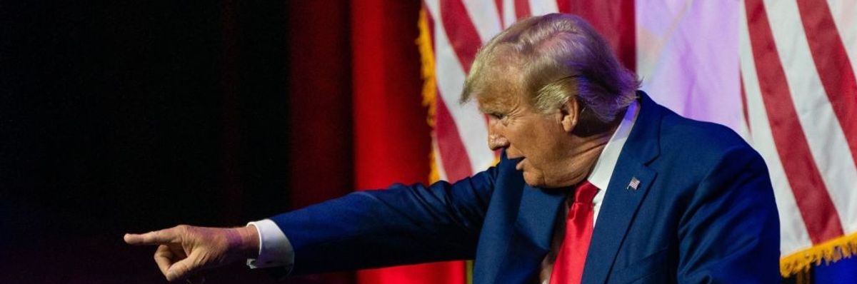 Donald Trump points from a stage.