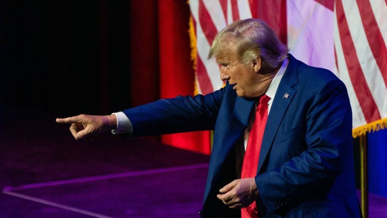 Donald Trump points from a stage.