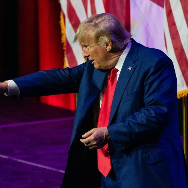 Donald Trump points from a stage.