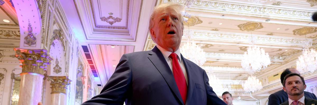 Donald Trump speaks to the media with his arms extended.