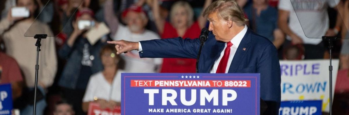 Donald Trump stands at a podium and points left.