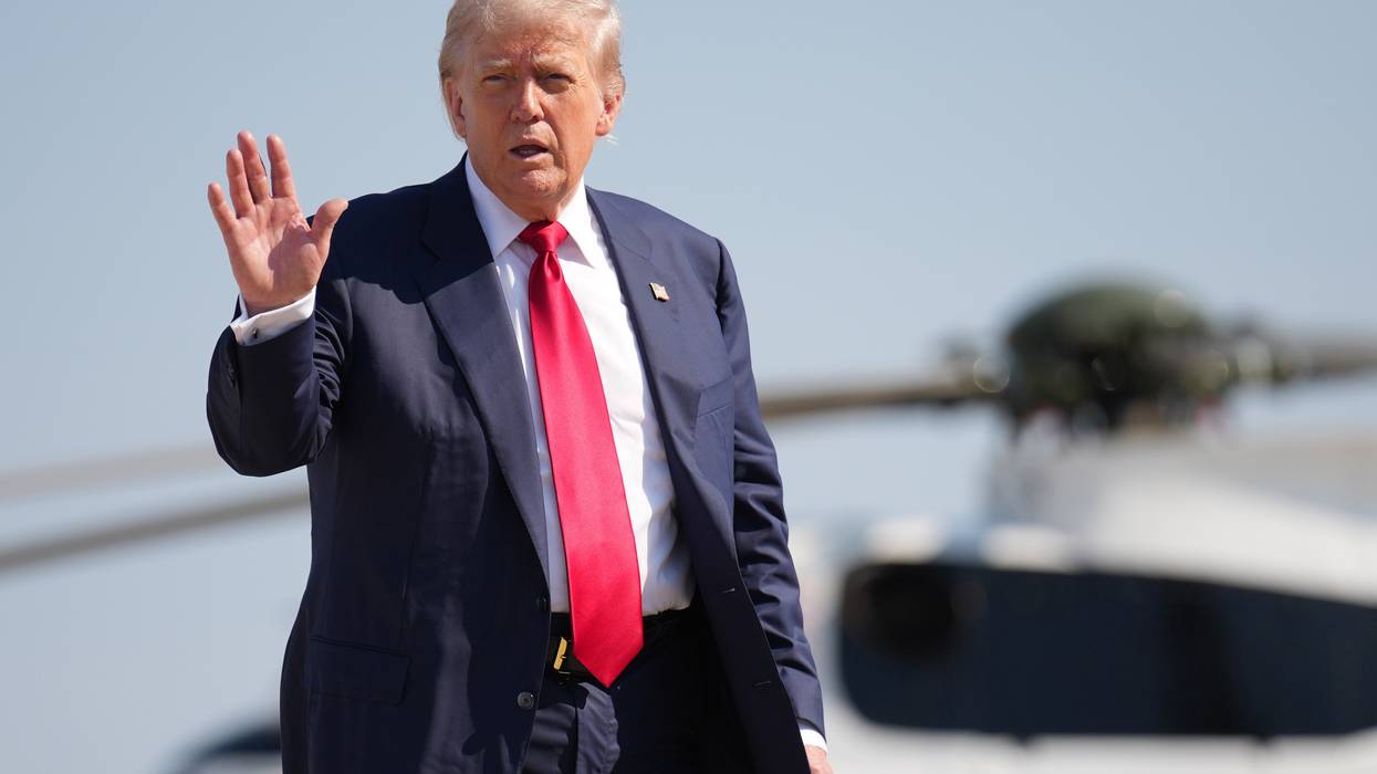 Donald Trump waves while wearing red tie.