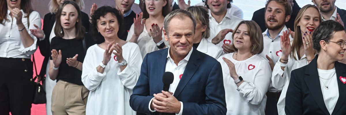 Donald Tusk holds  a microphone surrounded by supporters.