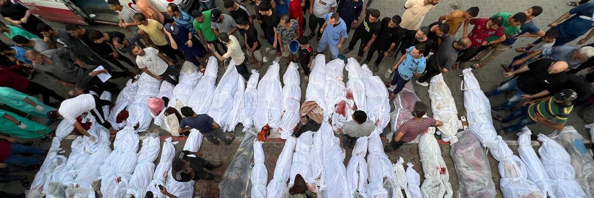 Dozens of Palestinian bodies wrapped in white sheets are lined up in the street
