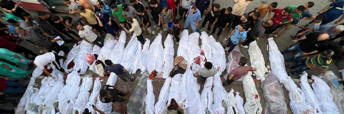 Dozens of Palestinian bodies wrapped in white sheets are lined up in the street