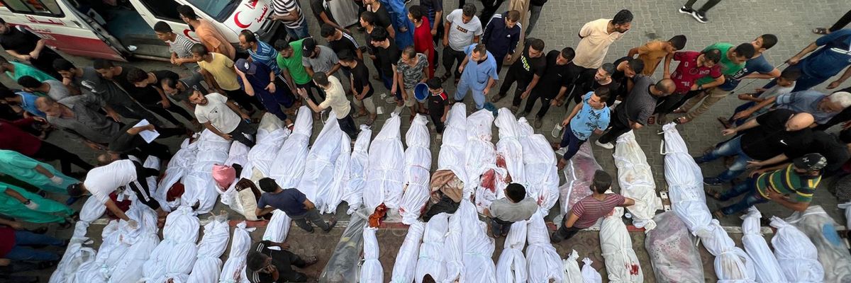 Dozens of Palestinian bodies wrapped in white sheets are lined up in the street