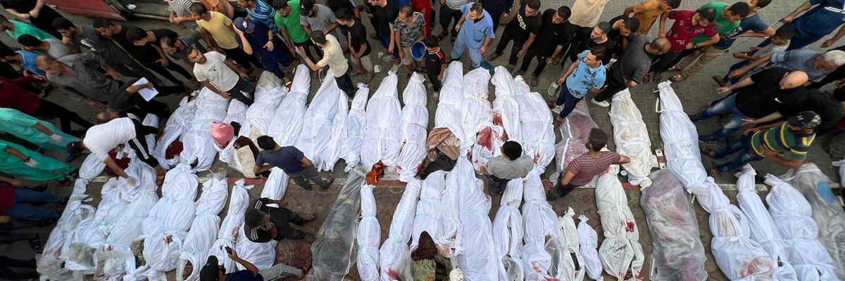 Dozens of Palestinian bodies wrapped in white sheets are lined up in the street