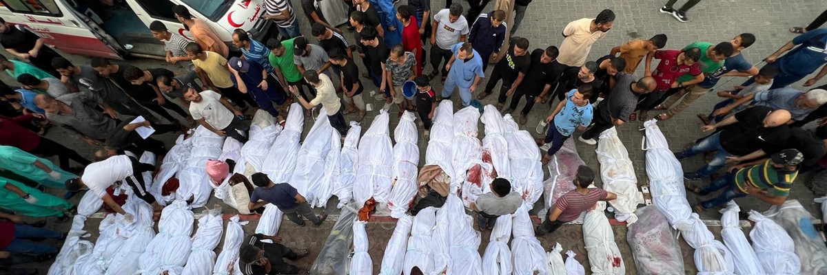 Dozens of Palestinian bodies wrapped in white sheets are lined up in the street