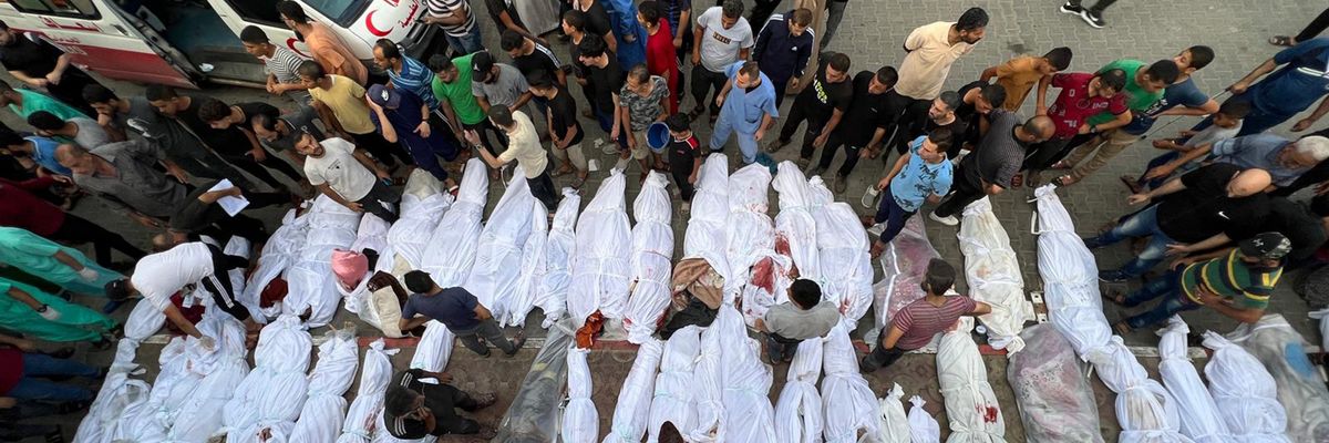Dozens of Palestinian bodies wrapped in white sheets are lined up in the street