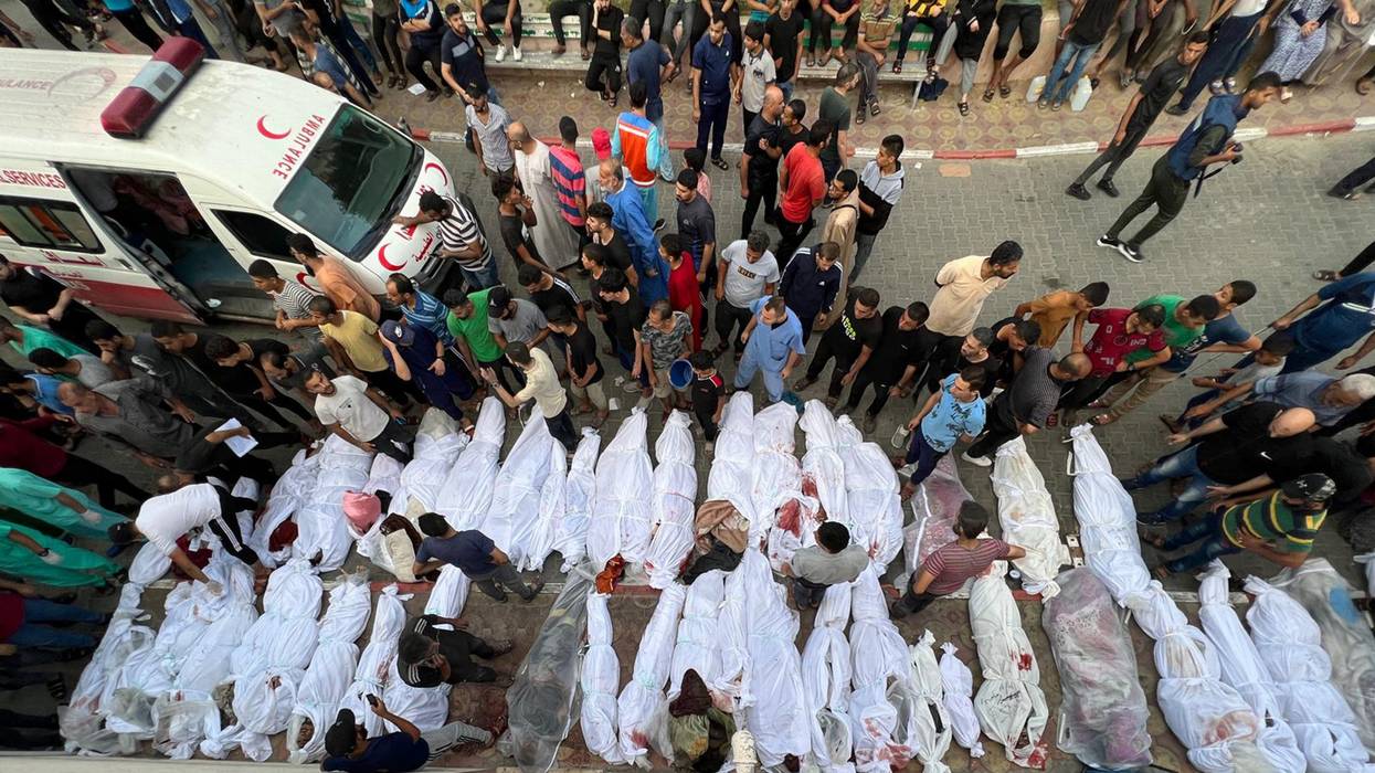 Dozens of Palestinian bodies wrapped in white sheets are lined up in the street