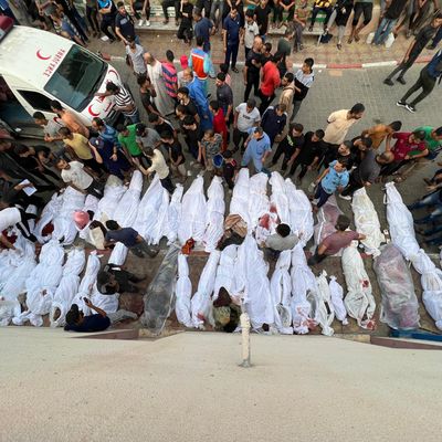Dozens of Palestinian bodies wrapped in white sheets are lined up in the street