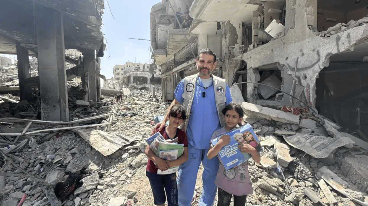Dr. Adam Hamawy poses for a photo with two Palestinian children in obliterated Gaza