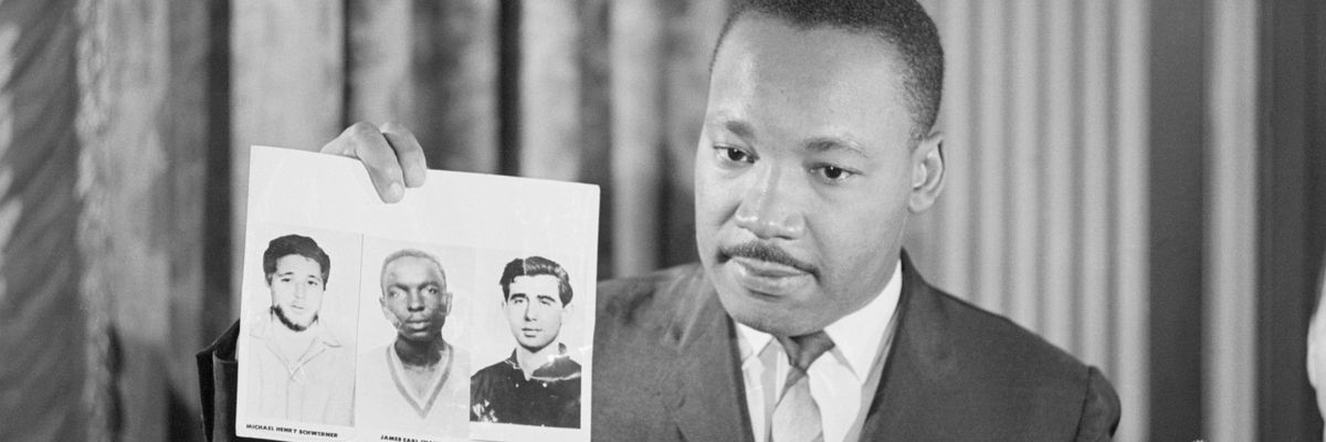 Dr. Martin Luther King Jr. holds a picture of Michael Schwerner, James Chaney, and Andrew Goodman at press conference.