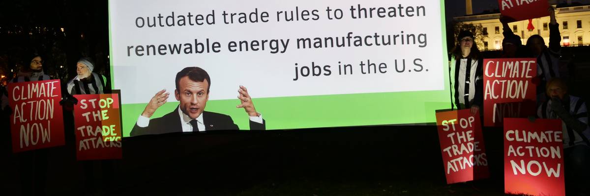 During a rally outside the White House on December 1, 2022, demonstrators urge French President Emmanuel Macron to stop using trade rules to block climate action.
