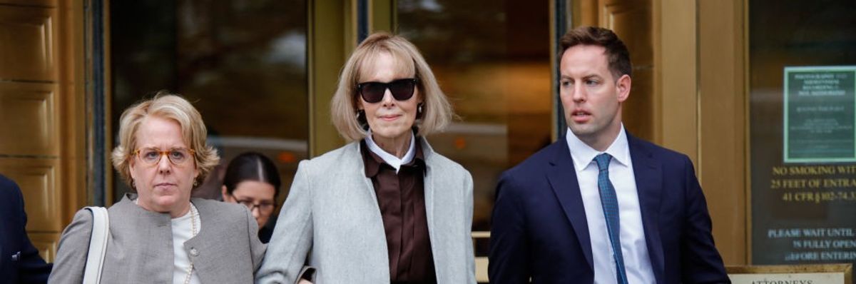 E. Jean Carroll leaves a court building flanked by a man and woman in professional dress.