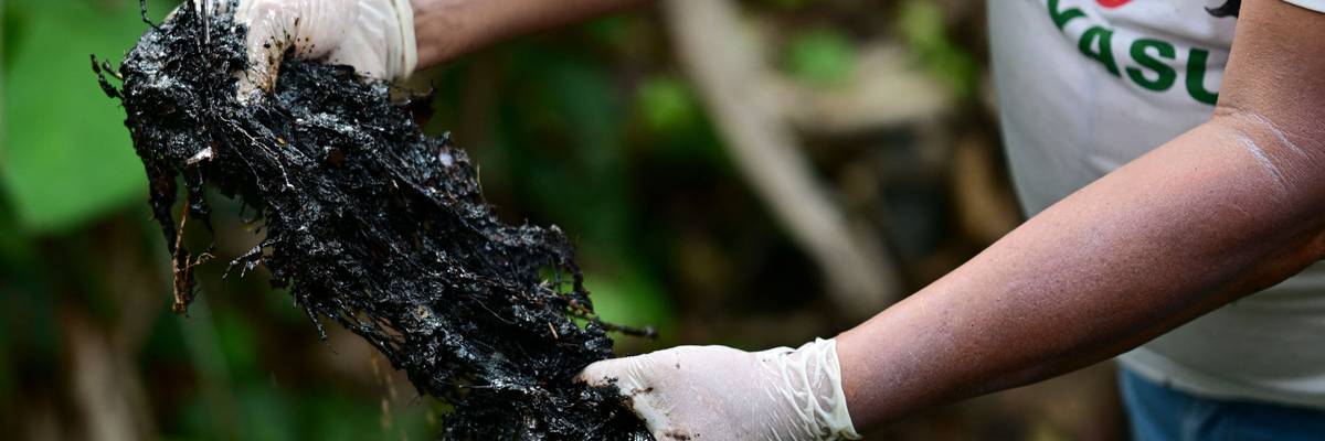 Ecuadorean activist Donald Moncayo Jimenez, chief coordinator of the Union of People Affected by Texaco, shows hydrocarbon waste over an outdoor pool used in the oil drilling process