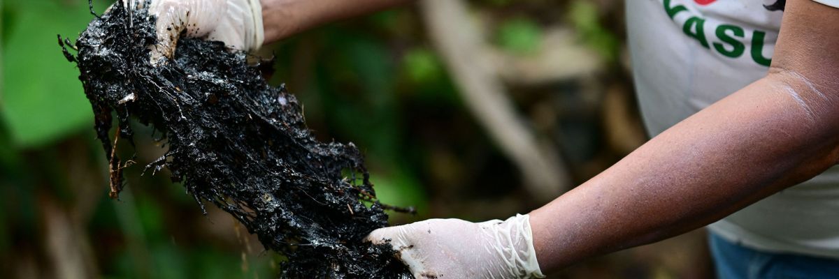 Ecuadorean activist Donald Moncayo Jimenez, chief coordinator of the Union of People Affected by Texaco, shows hydrocarbon waste over an outdoor pool used in the oil drilling process