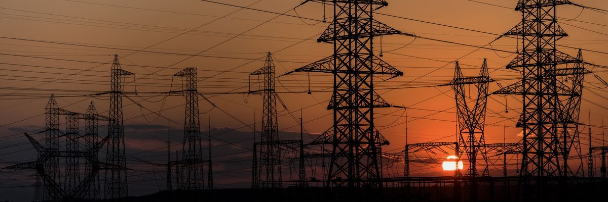 Electricity transmission lines are shown at sunset.