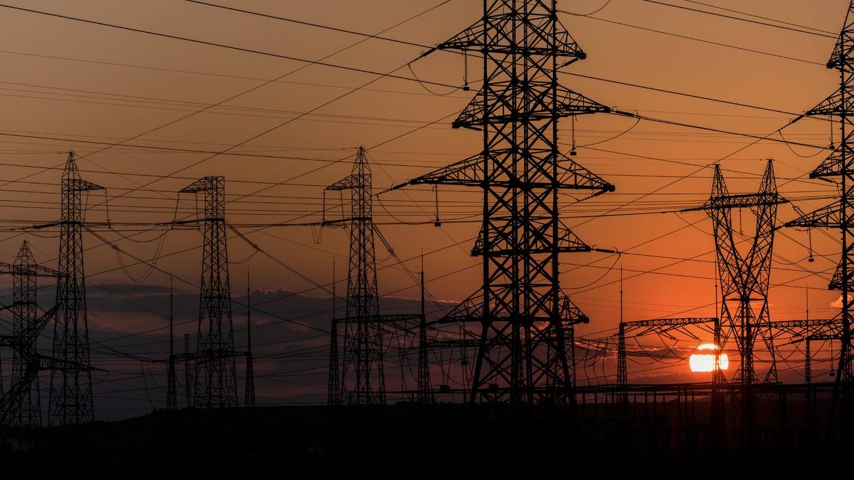 Electricity transmission lines are shown at sunset.