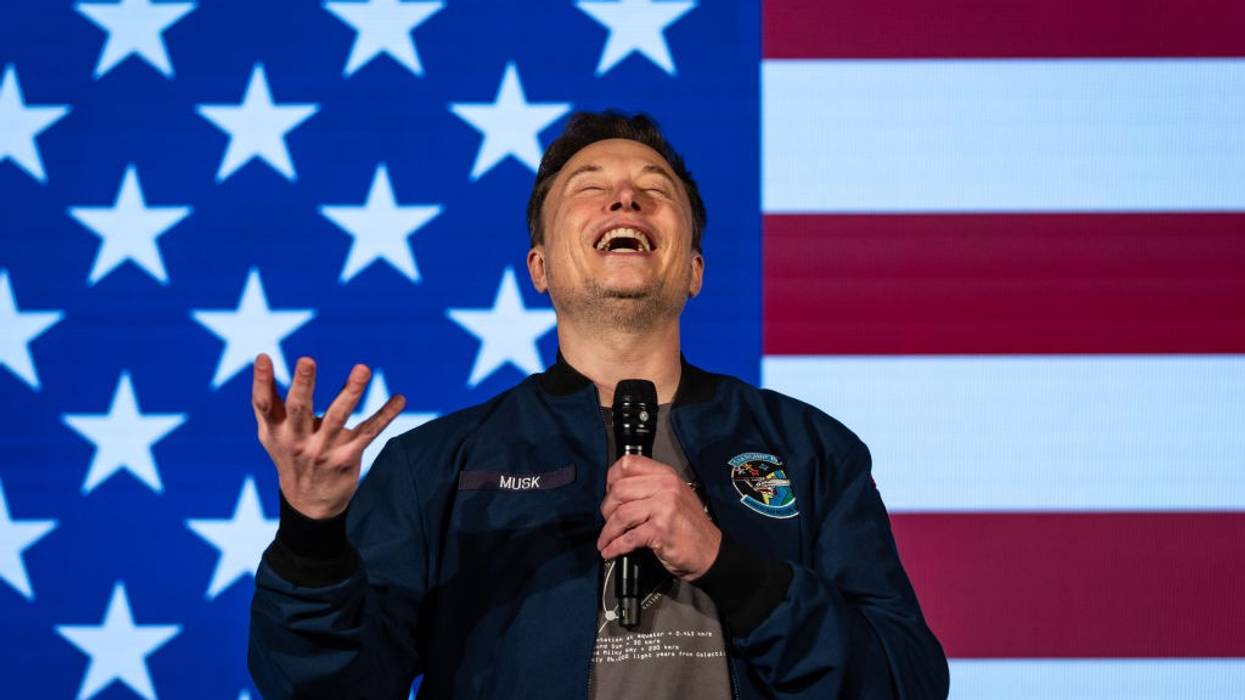 Elon Musk smiling in front of American Flag