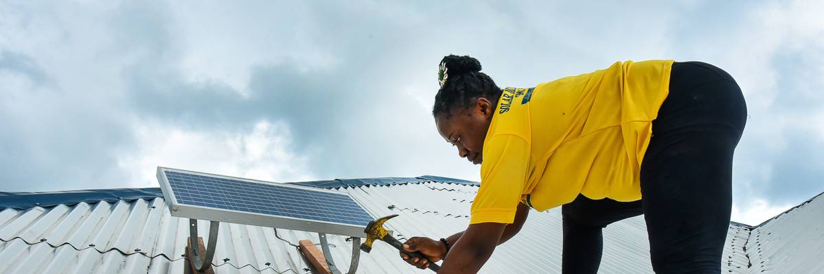 Eposi Njoh Monyengi fixes a solar panel on the roof of a house in Tiko, Cameroon on May 24, 2022.