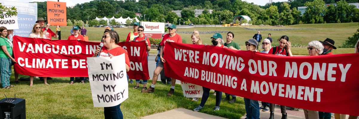 EQAT activists stand in a field with signs promising to move money from Vanguard.