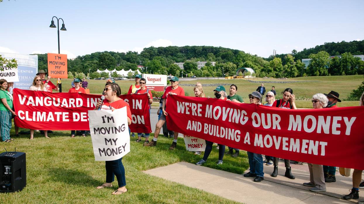 EQAT activists stand in a field with signs promising to move money from Vanguard.