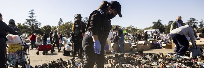 Evacuees from the Eaton Fire dwell among heaps of clothes displayed on the ground at a donation center in Santa Anita Park, Arcadia, California.
