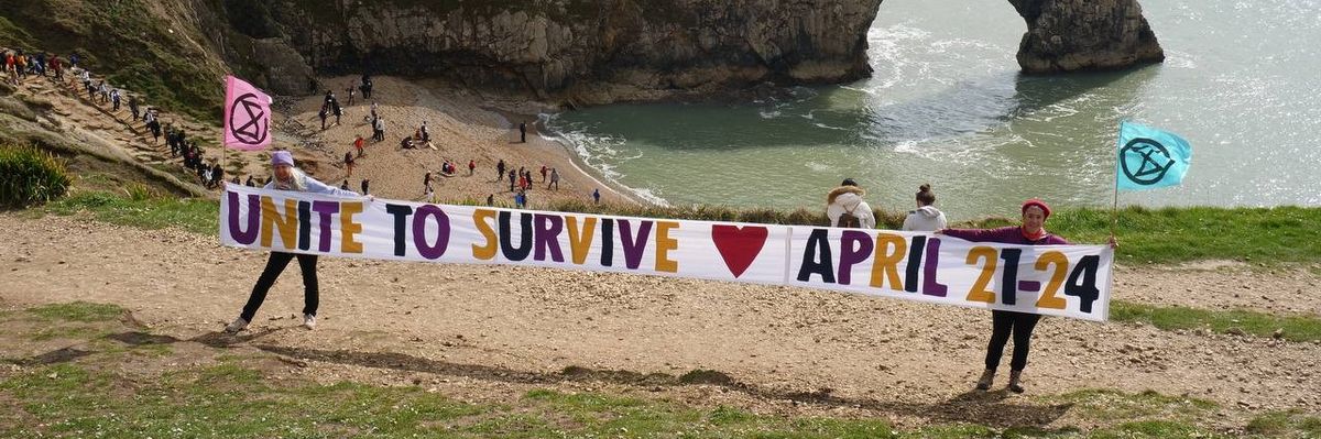 Extinction Rebellion campaigners hold a "Unite to Survive" banner at Durdle Door in Dorset, England on April 6, 2023.
