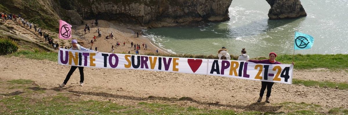 Extinction Rebellion campaigners hold a "Unite to Survive" banner at Durdle Door in Dorset, England on April 6, 2023.​