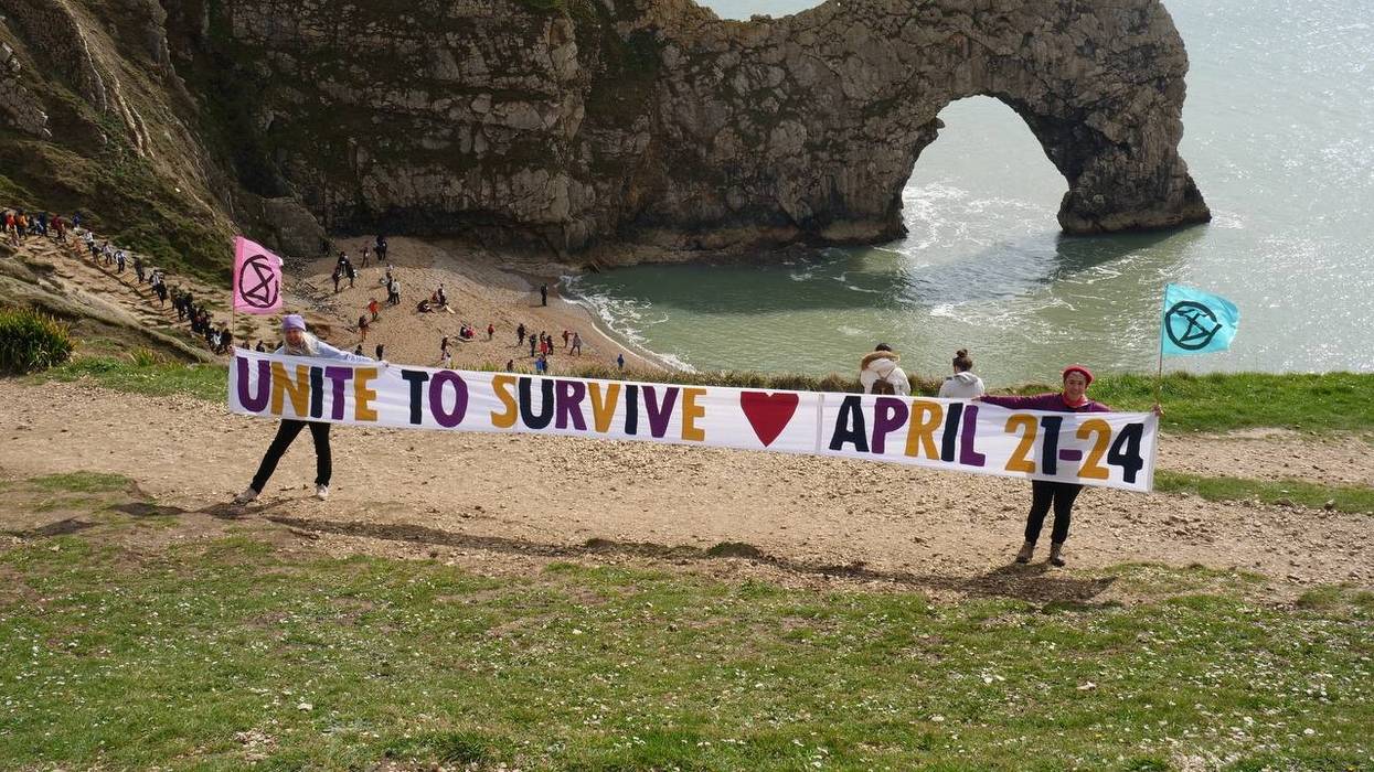Extinction Rebellion campaigners hold a "Unite to Survive" banner at Durdle Door in Dorset, England on April 6, 2023.