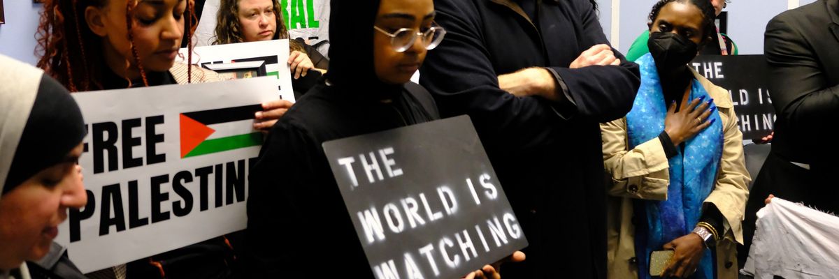 Faith leaders and activists hold signs saying "free Palestine" and "the world is watching"