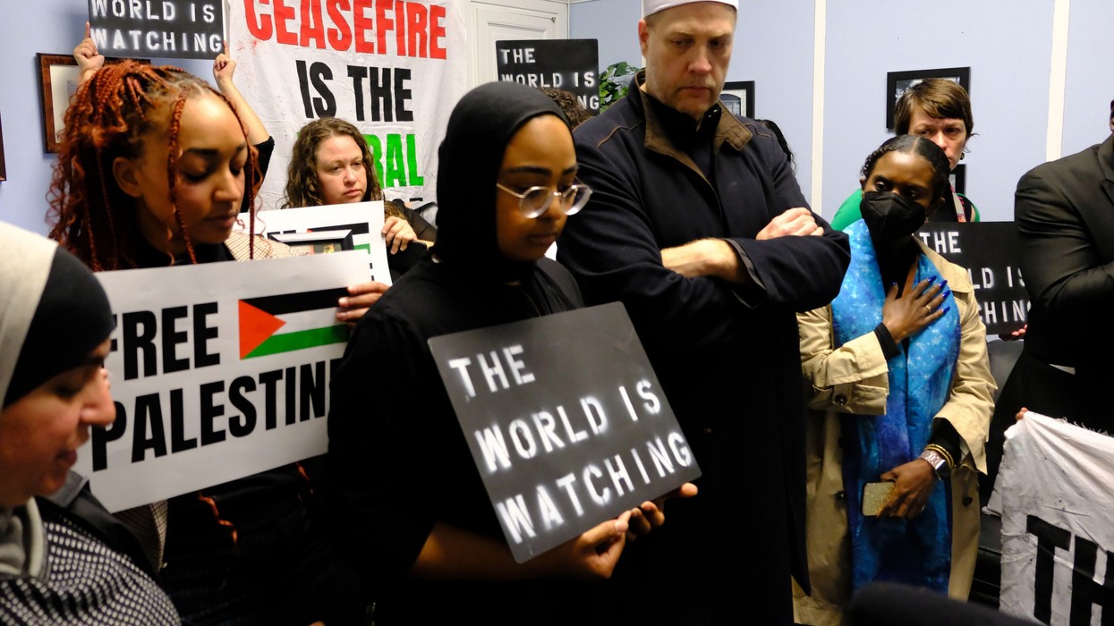 Faith leaders and activists hold signs saying "free Palestine" and "the world is watching"