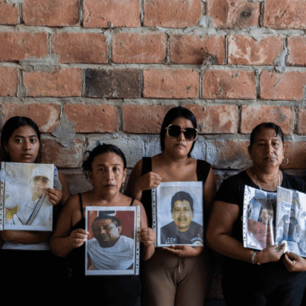Family members hold photos of their loved ones, who have been missing at sea since January 20, 2026, when their fishing boat "went up in smoke" in international waters.