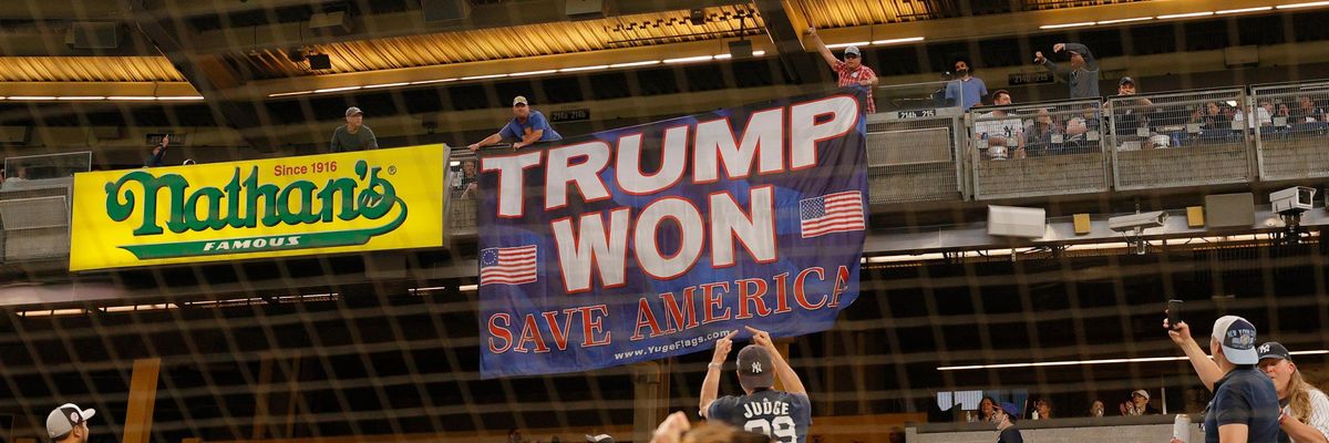 Fans unroll a banner in support of former U.S. President Donald Trump during a baseball game.