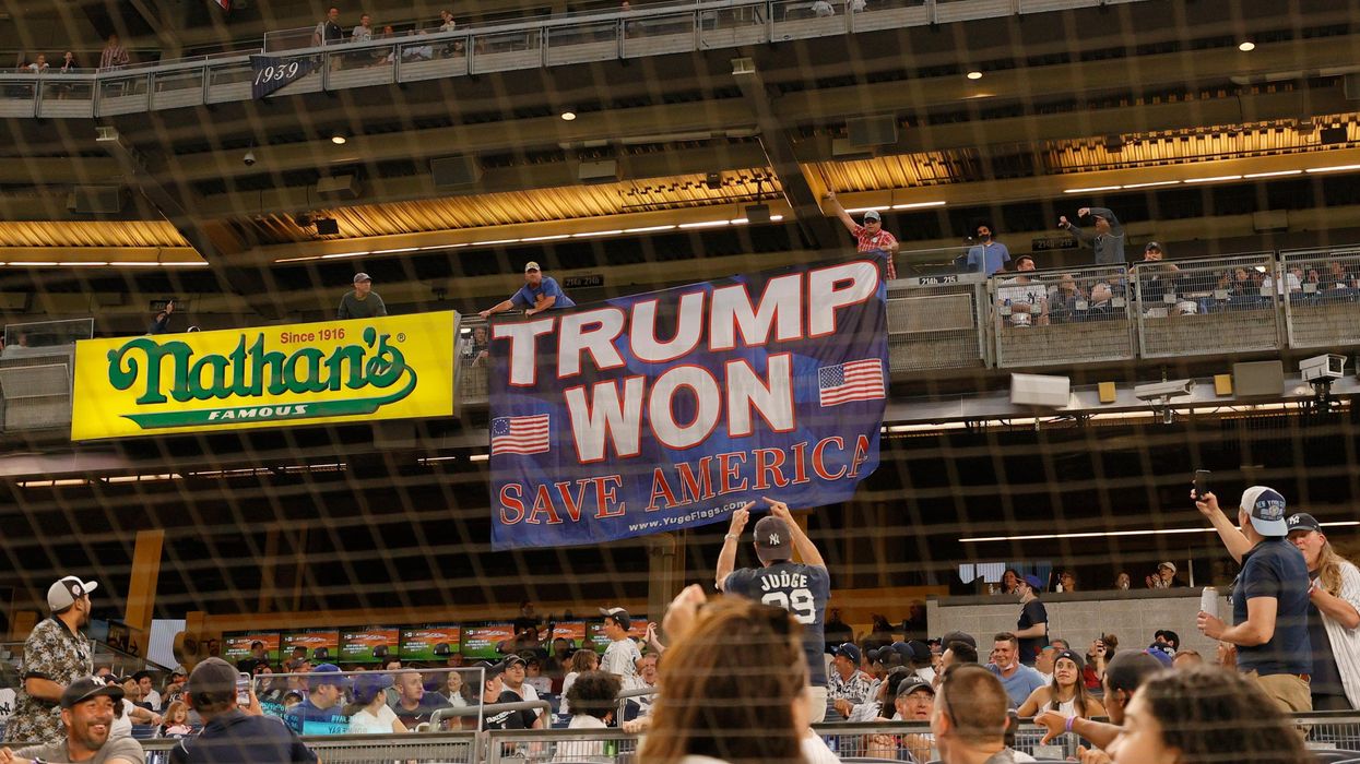 Fans unroll a banner in support of former U.S. President Donald Trump during a baseball game.