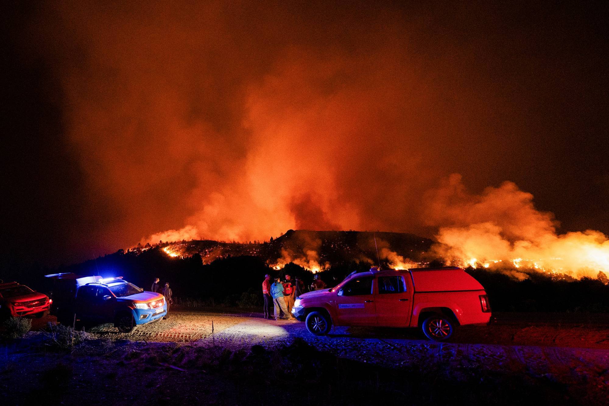 Firefighters fight a fire in the mountains of Argentina at night.