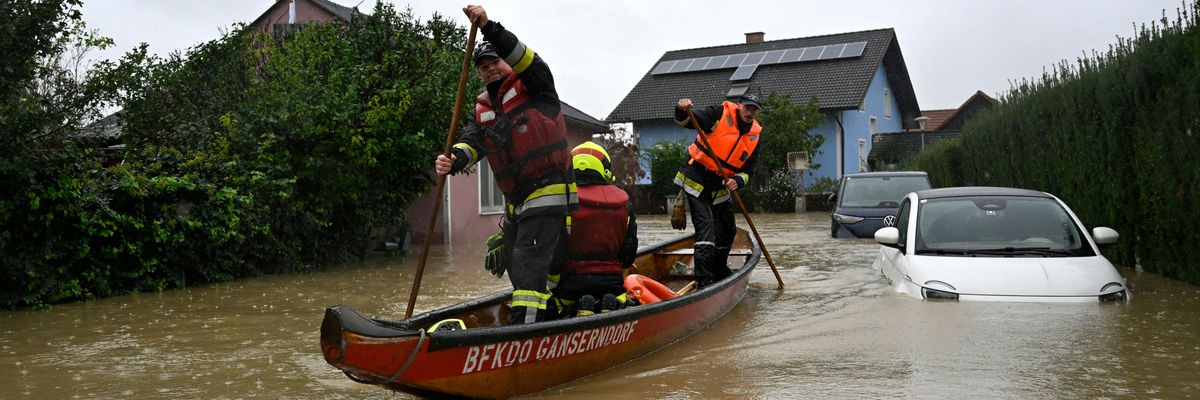 Firefighters in a boat make their way past a car submerged by the floods