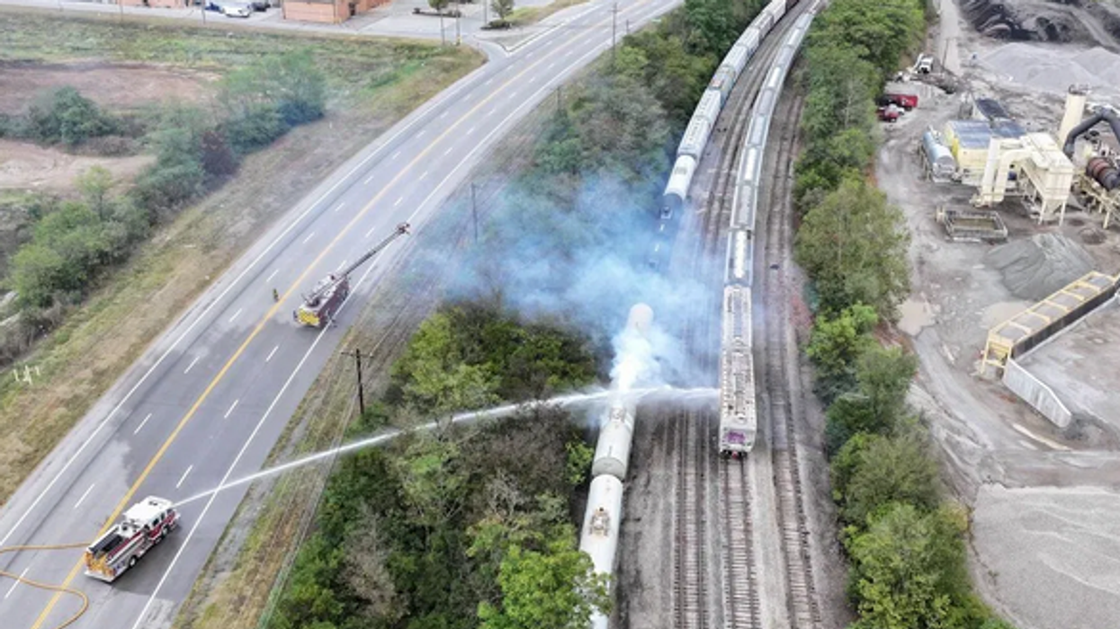 firetrucks spray down a railcar that had leaked a toxic chemical