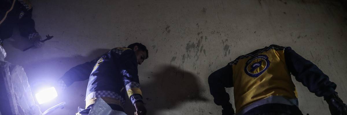 First responders carry the body of a child killed by a U.S. raid in Syria