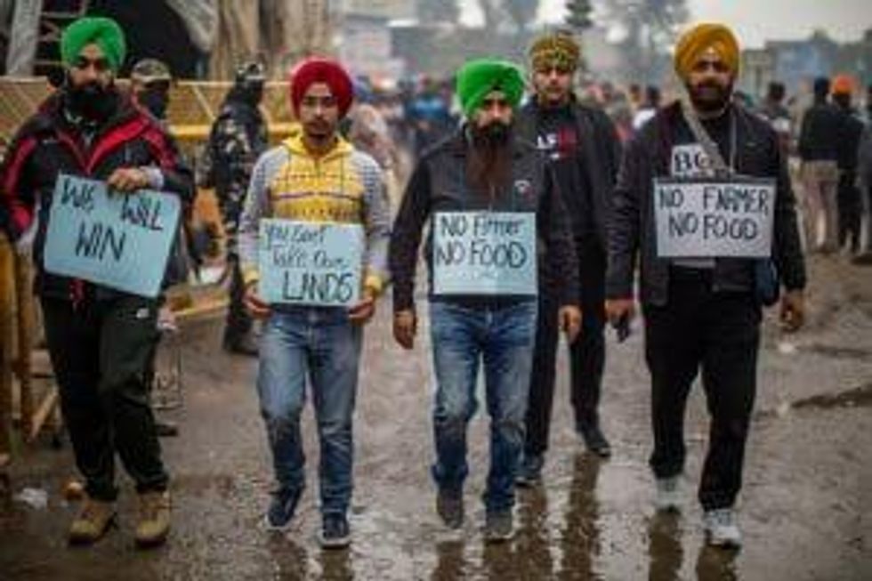 Five men wearing turbans are walking with signs saying