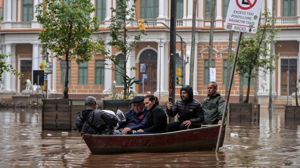 five people in a small boat in a flooded city