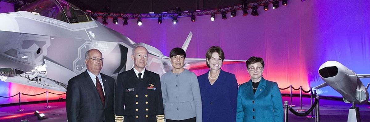 Five people stand in front of an F-35 aircraft. 