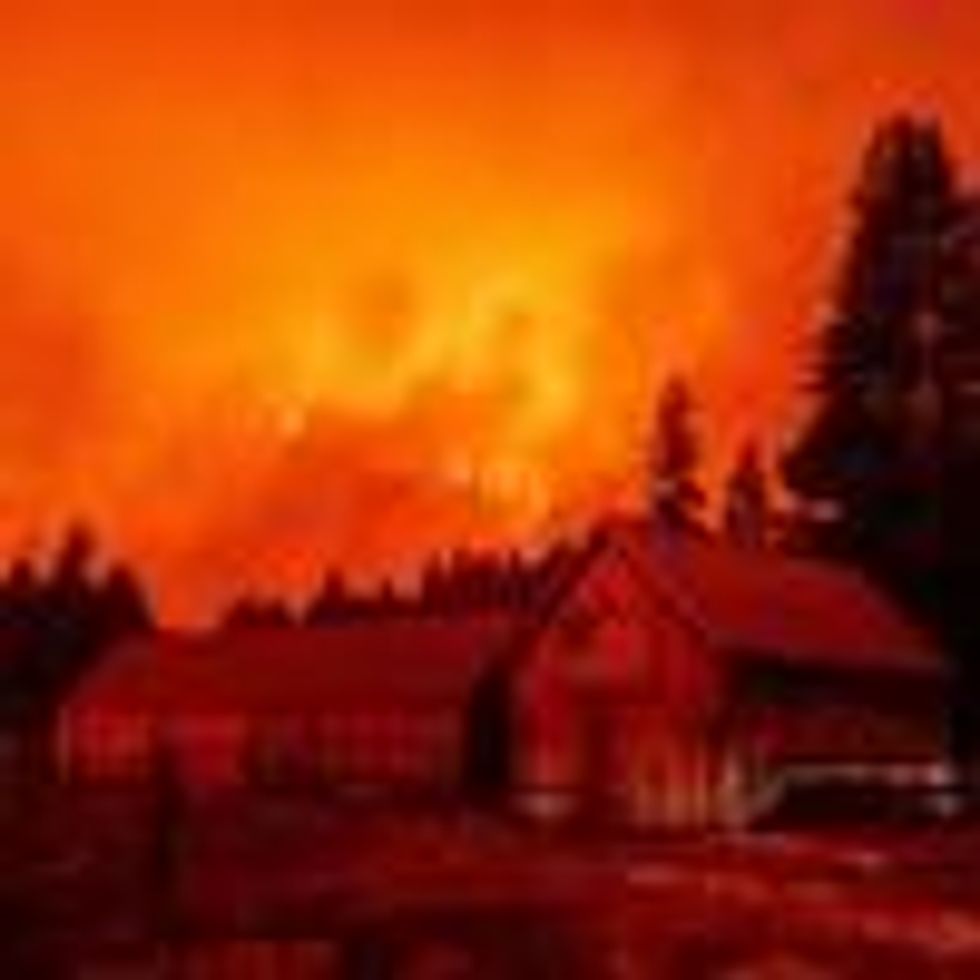 Flames rip across a hillside behind a building donning a U.S. flag as the Caldor Fire pushes into South Lake Tahoe, California on August 30, 2021. (Photo: Josh Edelson/AFP via Getty Images)