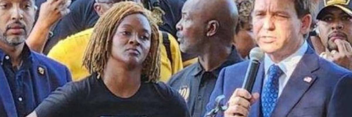 Florida State Rep. Angie Nixon angrily listens to Gov. Ron DeSantis at a vigil for victims of the latest racist shooting.